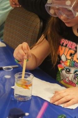 Girl stirring thermoplastic polymer with popsicle stick.