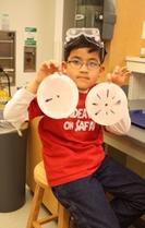 Boy holding two plates with different colours on them.