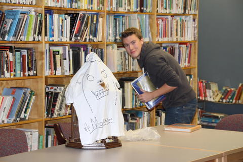 Student from Arnprior High School from Arnprior Ontario hiding paper moles for school wide mole hunt in a book shelf