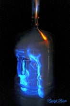 A bottle with blue flames inside and coming out of the top.
