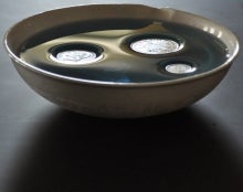 Three coins floating on water in a bowl.
