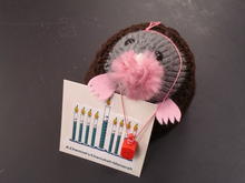 A mole made out of yarn holding an sign that reads a chemists Chanukah menorah which has graduated cylinders to represents the candles of a menorah 