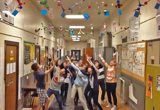 Students standing underneath handmade molecules in school hallway.