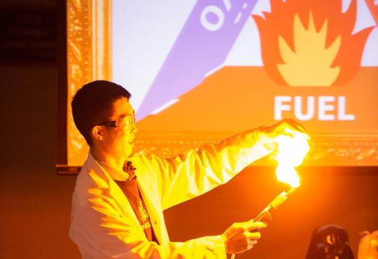 guy in a lab coat holding a glowing flame