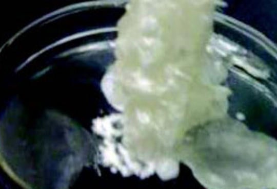 pouring a white solution out of a flask in which the solution appears to be crystallizing 