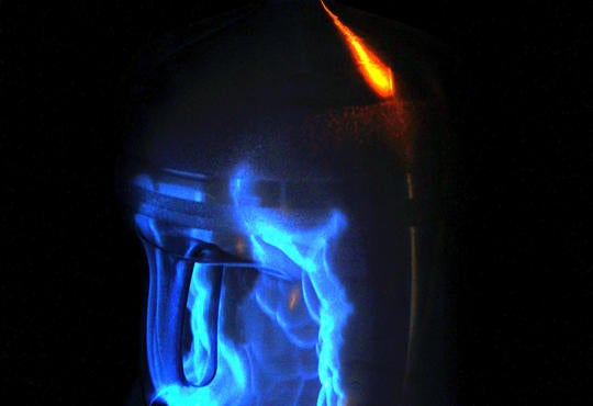 a photo of a whoosh bottle - a large clear water bottle with a blue flame in a darken room  