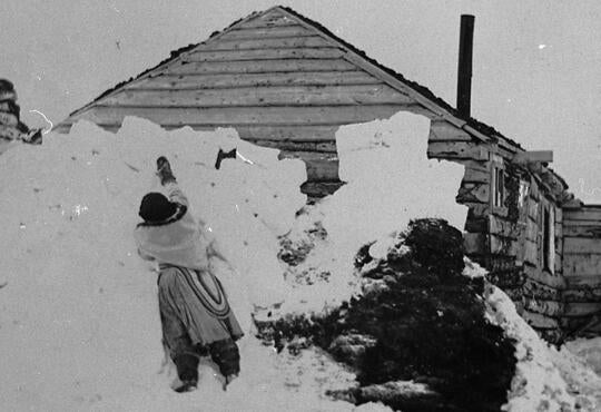 Inuit woman in Okak, Nunatsiavut (possibly one of Chaim’s ancestors), packing snow blocks around her house as insulation.