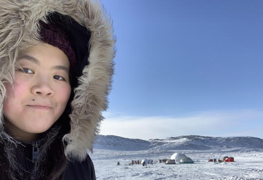Katie Yu in front of a qaggiq (large communal igloo) near Iqaluit, NU.