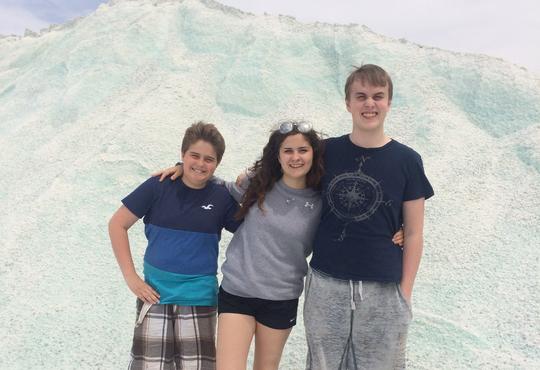 three teenagers in front of a large white hill of salt