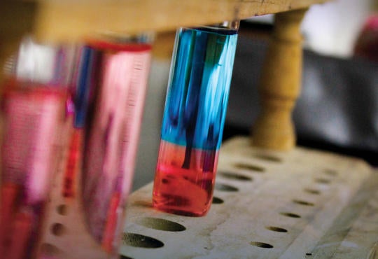 A close up photo of a test tube with two phase solution, clear blue on top and clear red on the bottom. 