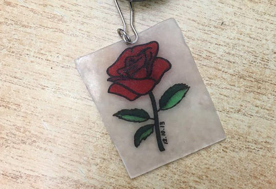 A red rose painted on a Shrinky Dink piece of plastic for a keychain