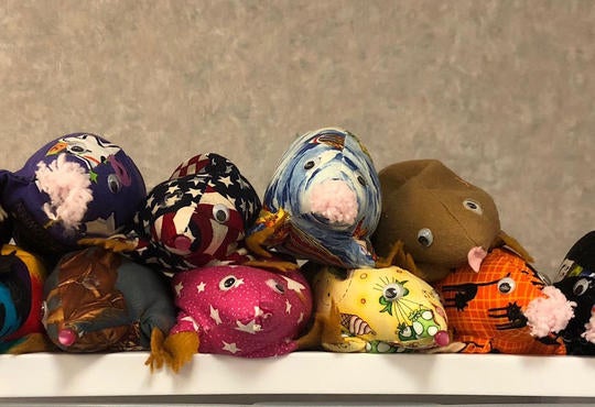 a 13 stuffed moles of different patterns all on a shelf