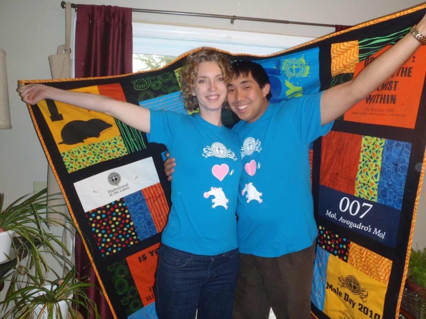 Man and woman holding ‘Mole Day’ quilt.