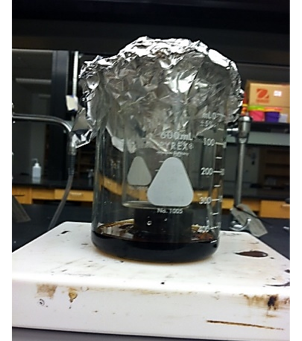 Aluminum foil, small beaker and liquid inside large beaker.