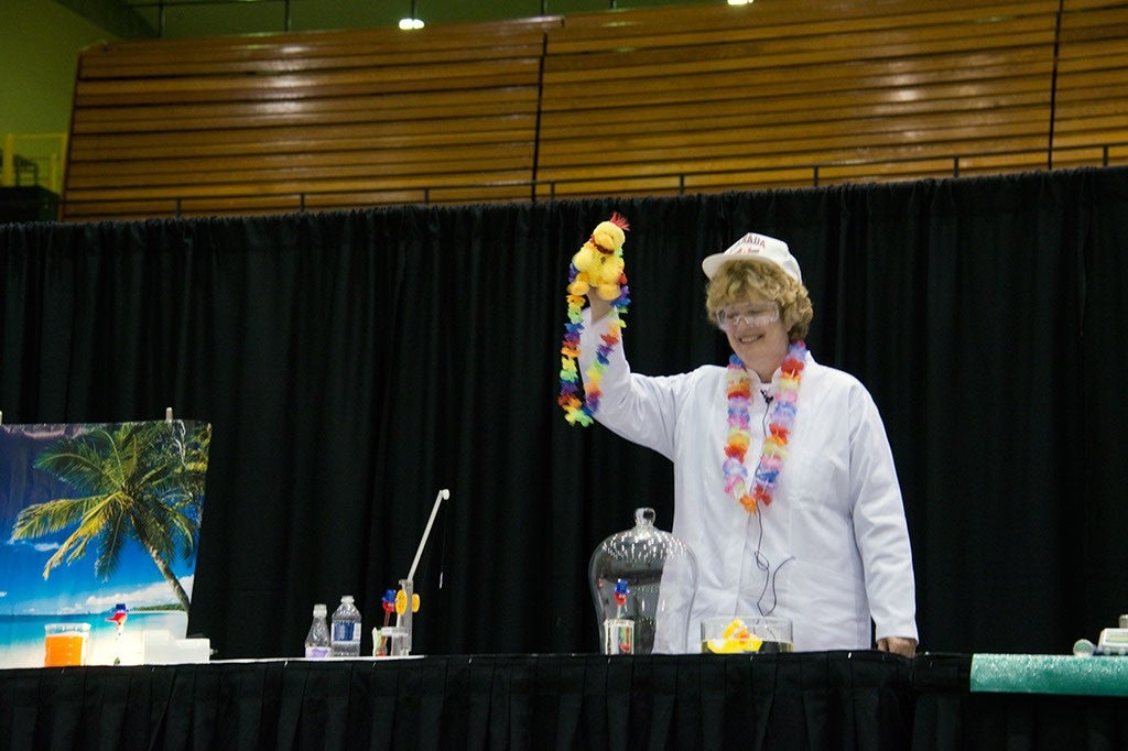 Woman giving chemistry demonstration holding toy duck.