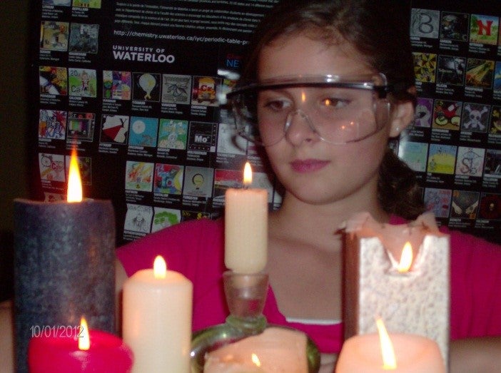 Girl standing behind candles.