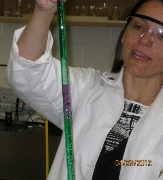 Woman holding different coloured solutions in burette.