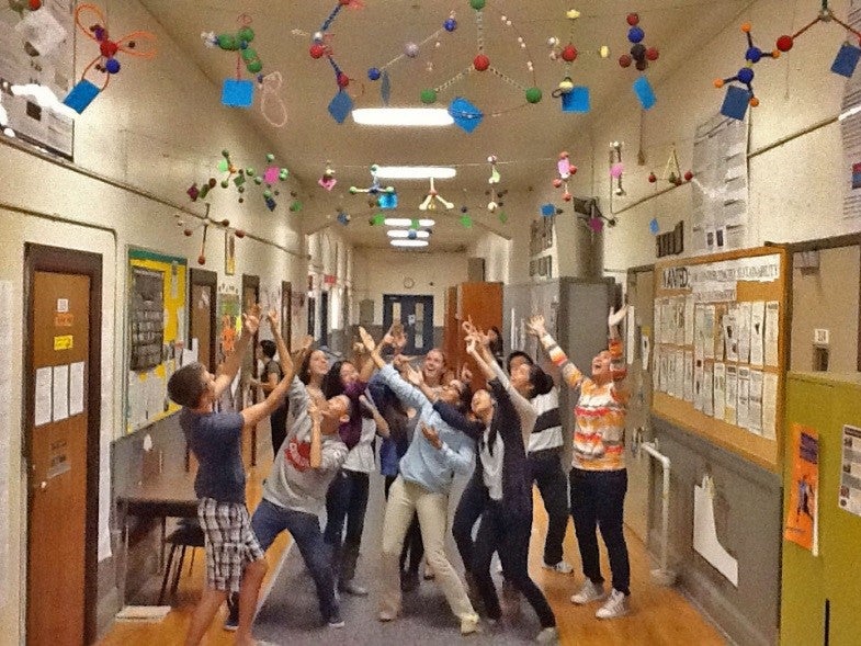Students standing underneath handmade molecules in school hallway.