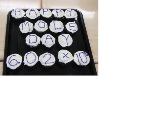 Cupcakes each with a letter that spells out the message “Happy Mole Day 6.02 x 10^23”.