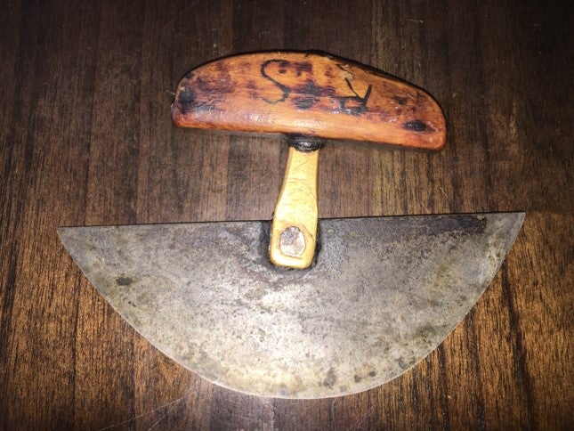 a semicircular metal blade and a wooden handle -- ulu