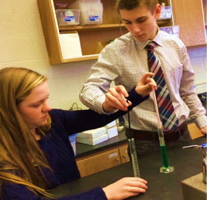 Students putting a straw into a graduated cylinder.