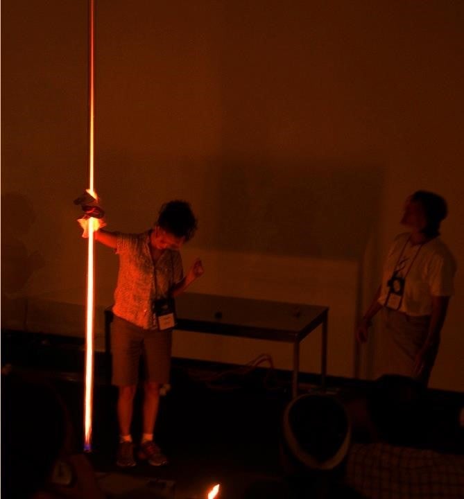 Woman holding long tube glowing red.