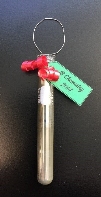 Test tube with ribbon, tag and metal lop attached to top.