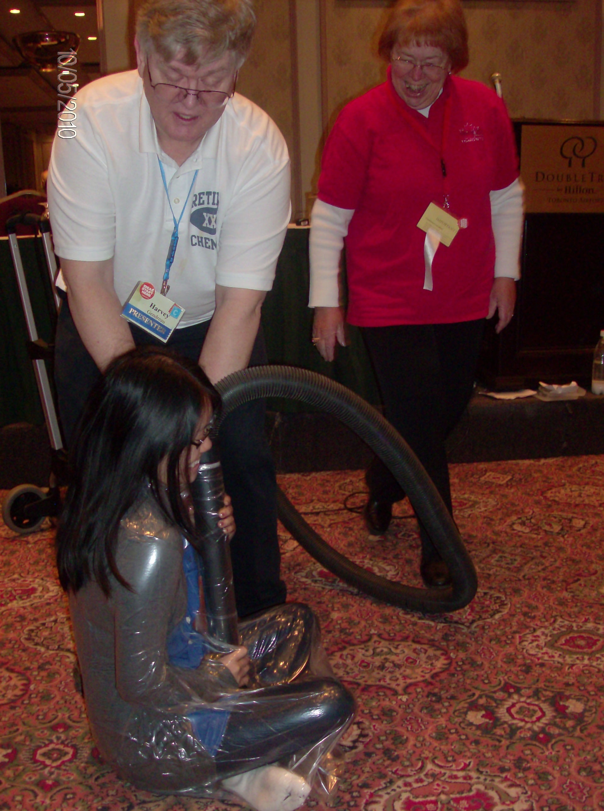 Harvey Gendreau using a shop vac to wrap someone in the audience in a plastic bag