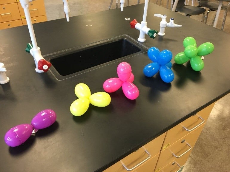 on a lab bench five models showing orbitals with colourful plastic eggs
