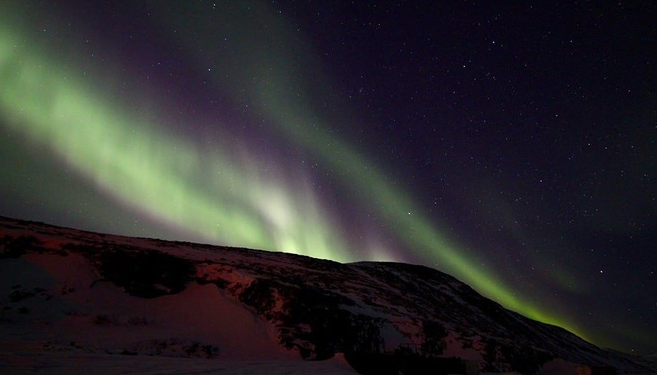 A picture showing the blue and green layers of an Aurora over the horizon at Nain, Nunatsiavut.