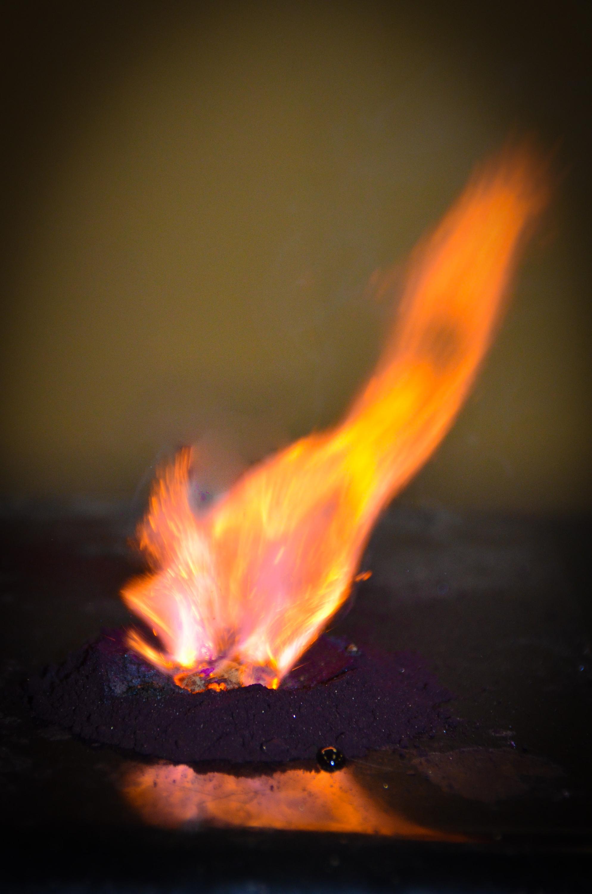 medium-sized orange flame coming out a small pile of grey powder