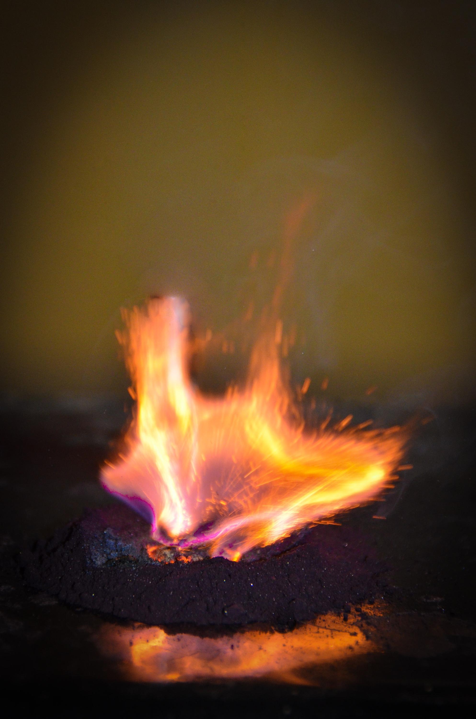 large orange flame coming out a small pile of grey powder