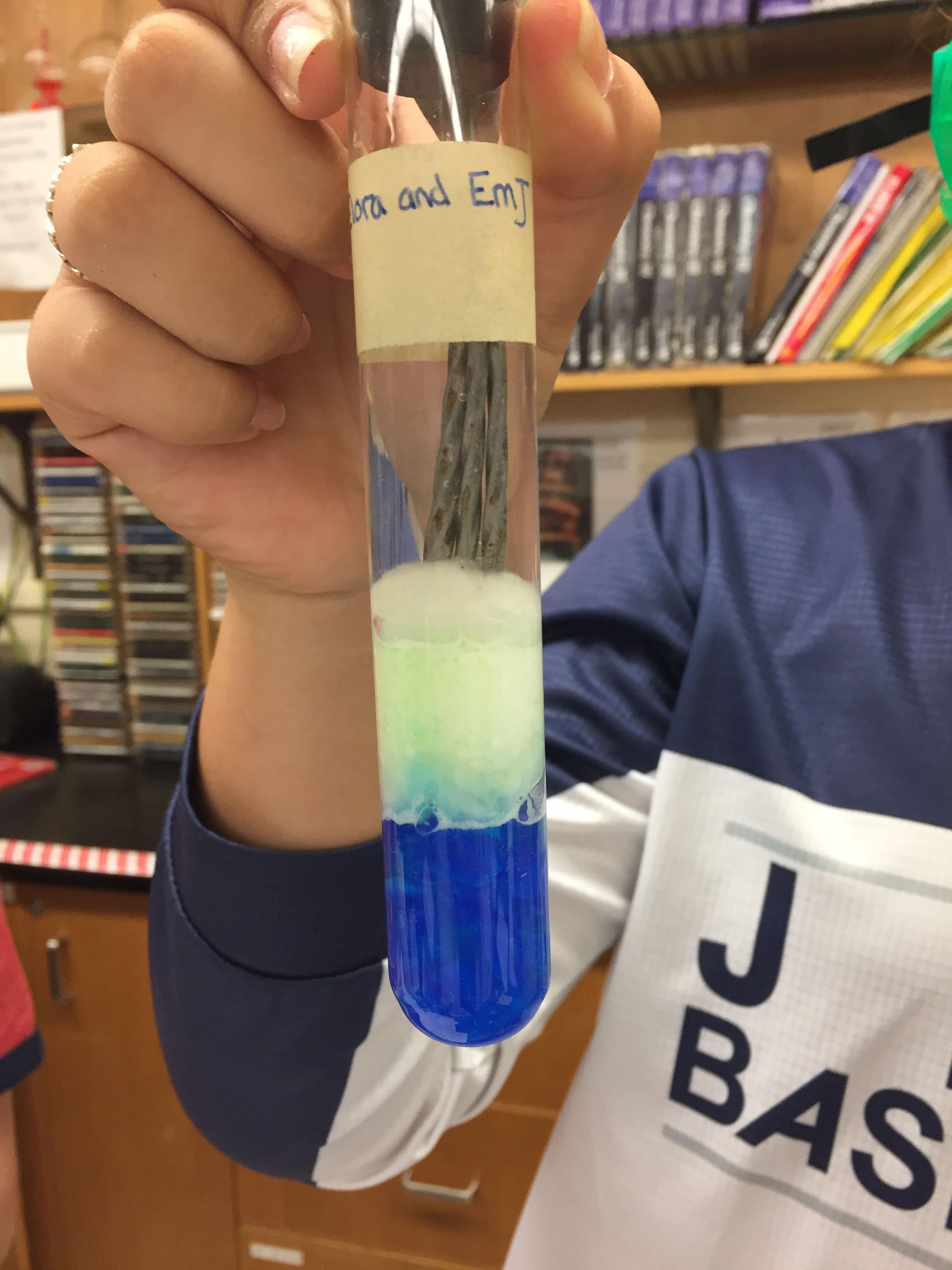 Test tube setup with layering of copper(II) sulfate (bottom), cotton, salt and three nails in water.