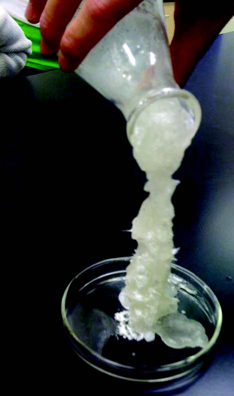 pouring a white solution out of a flask in which the solution appears to be crystallizing