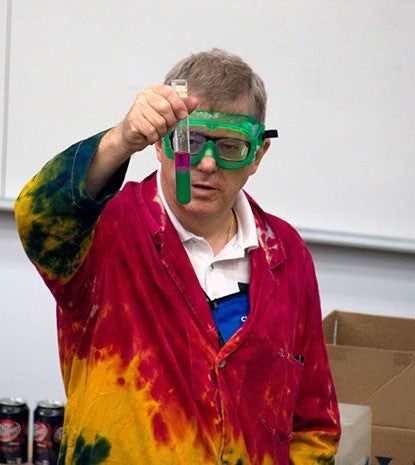 Andy Cherkas showing a solution with a red layer on top and a green layer on the bottom in a test tube.