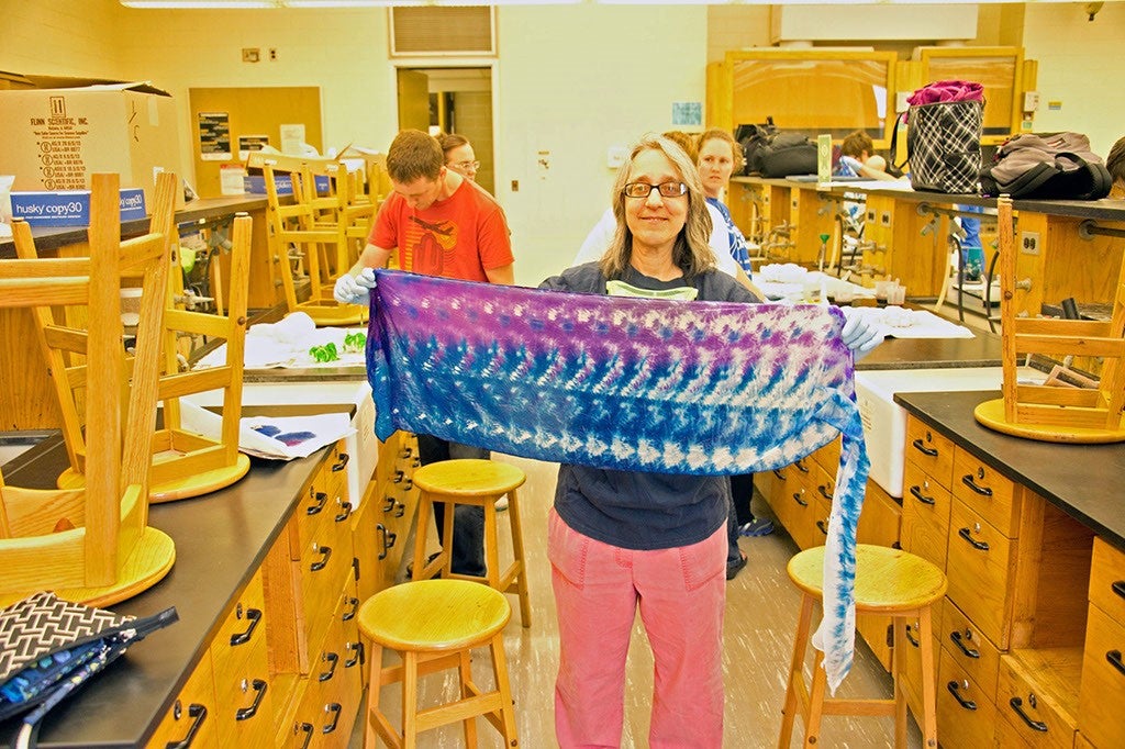 A ChemEd attendee holding up a tie-dyed purple and blue scarves.