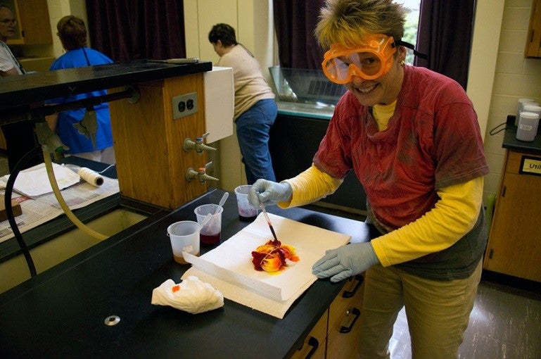 A ChemEd attendee using a pipette to add dye to a T-shirt in a lab setting.