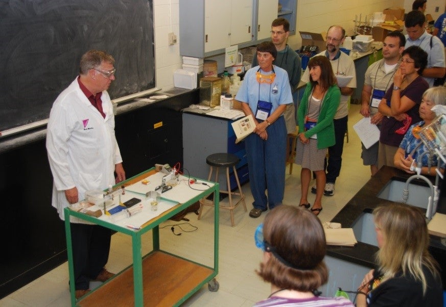 Bob Worley with a group of teachers standing around observing him do a demonstration at ChemEd 2013.
