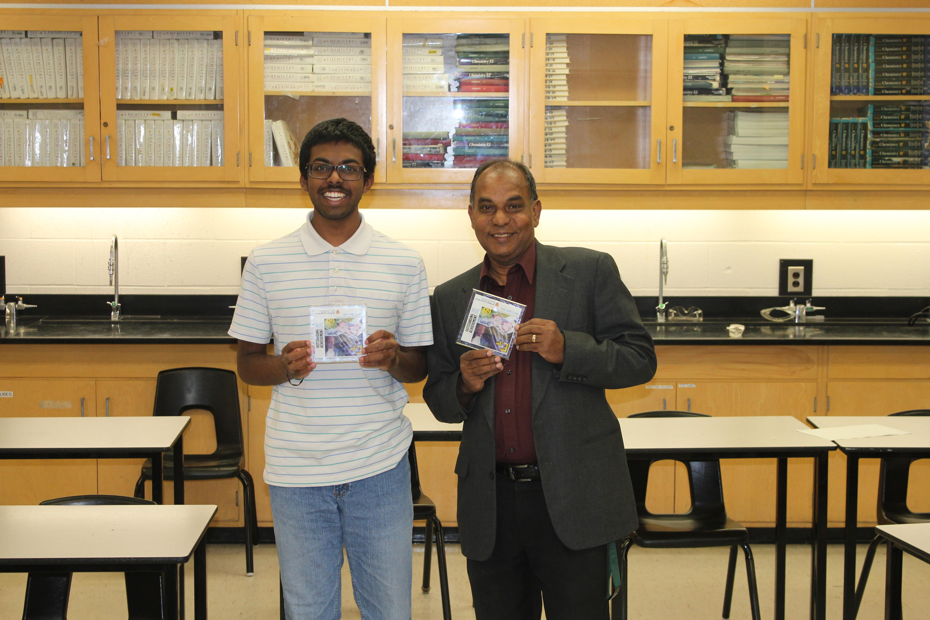 Student Yashan Chelliahpilla and his teacher Samuel Dijohn holding winning tiles in a chemistry lab