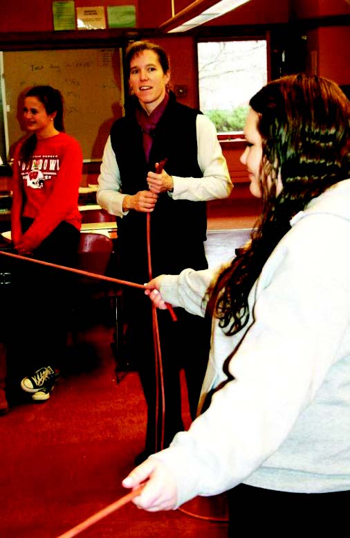 three students -- two pulling on the ends of a stretching tube with one pulling from the middle demonstrating a water molecule