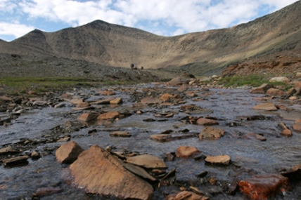 a photo of Ramah Bay showing rocks in a shallow river with a mountain in the background