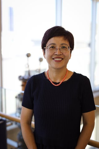 a woman in a black top and glasses smiling 