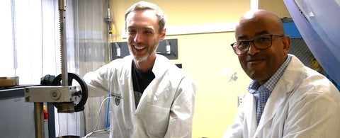 A man laughing in a white lab coat and Dr. Tizazu Mekonnen in a white lab coat