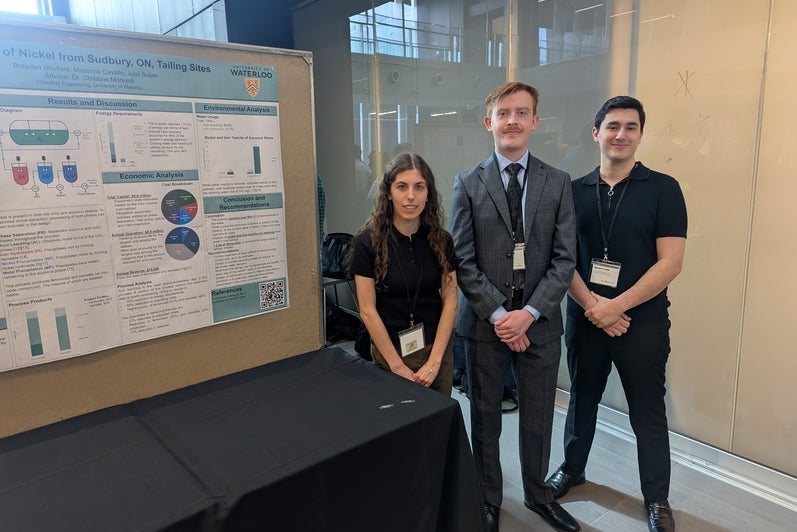 a woman and two men standing in front of a poster board