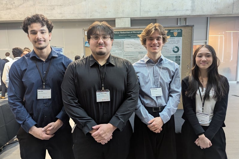a woman and three men standing in front of a poster board