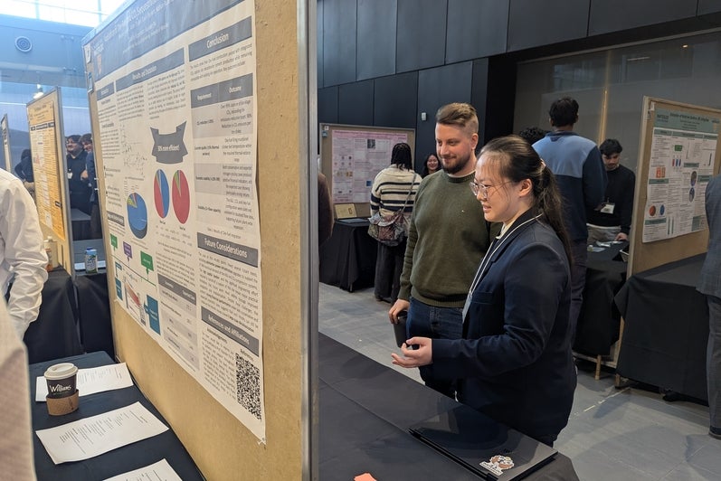 a man and woman looking at a poster board