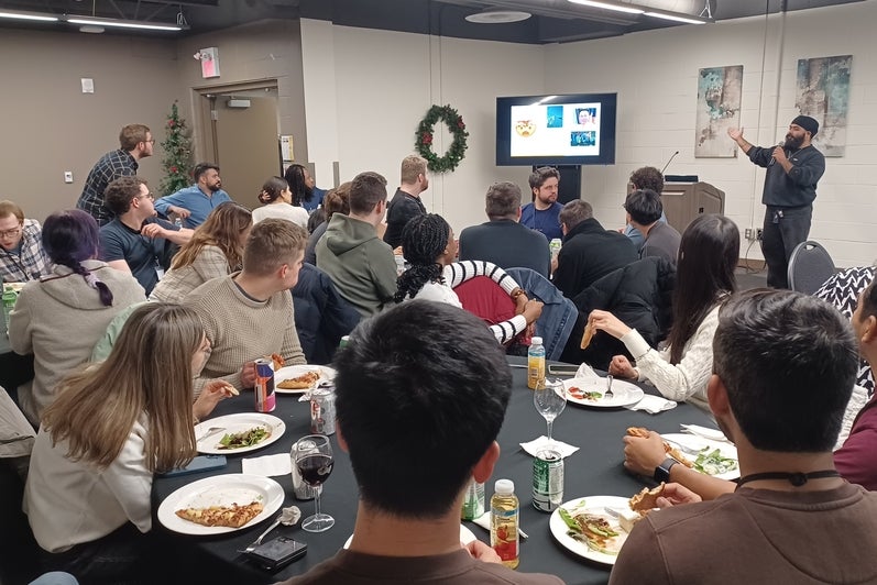 People sitting at tables a man has a microphone