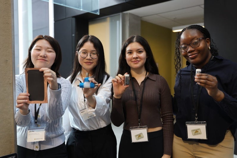 Four women smiling holding objects in their hands