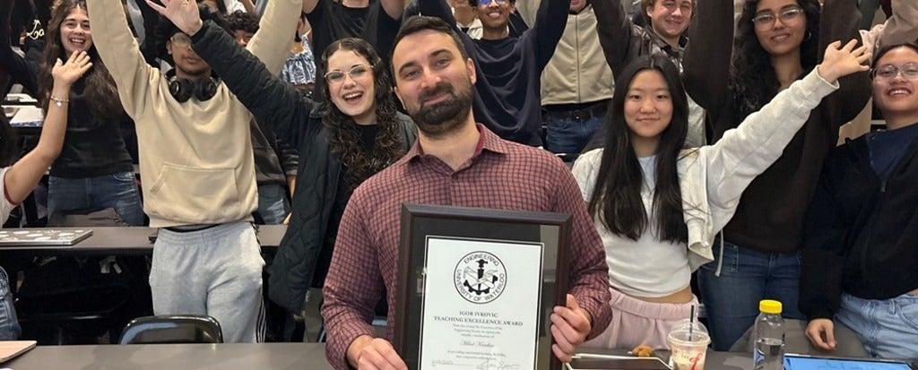 a man standing in front of a group of cheering students holding a plaque