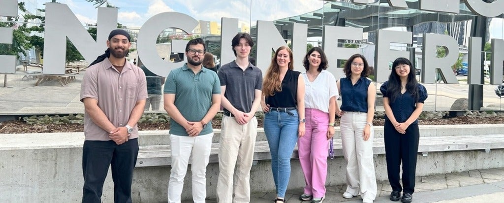 seven people standing in front of an engineering sign